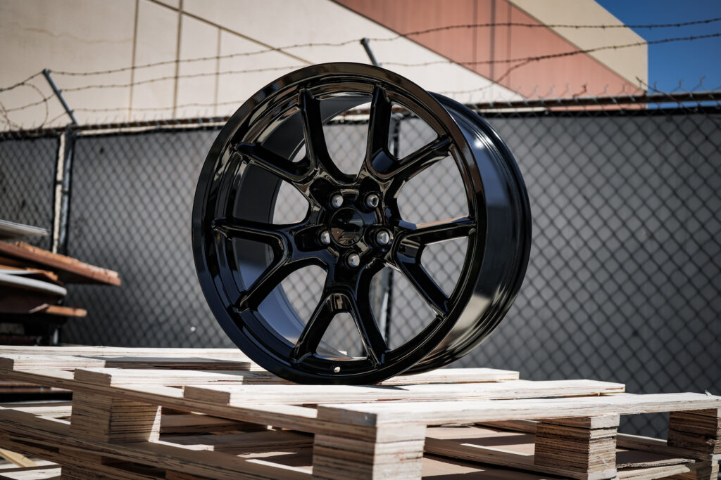 DSC00358 - Factory Reproductions FR66F replica wheel for dodge in gloss black in an industrial setting on a wooden pallet.